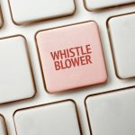 Una tastiera bianca con un tasto rosso che riporta la parola whistleblower